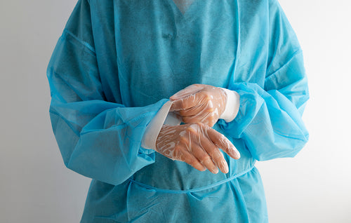 Profesional de salud con bata quirúrgica azul ajustándose guantes desechables de protección médica