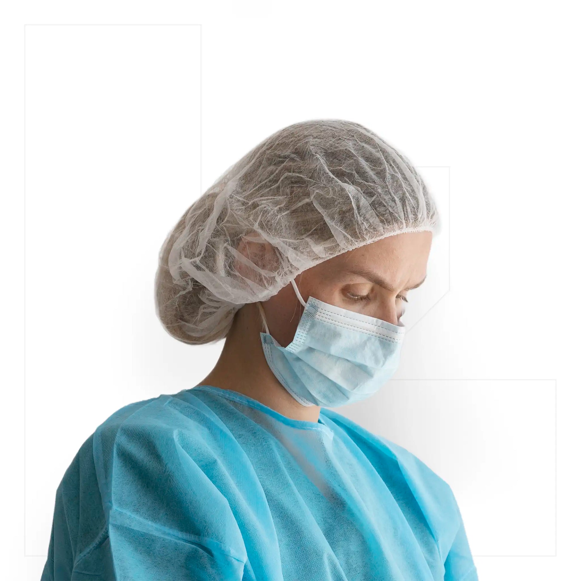 Mujer utilizando cofia desechable de polipropileno blanca Klinetix con ajuste elástico, mascarilla y bata azul en entorno sanitario controlado.